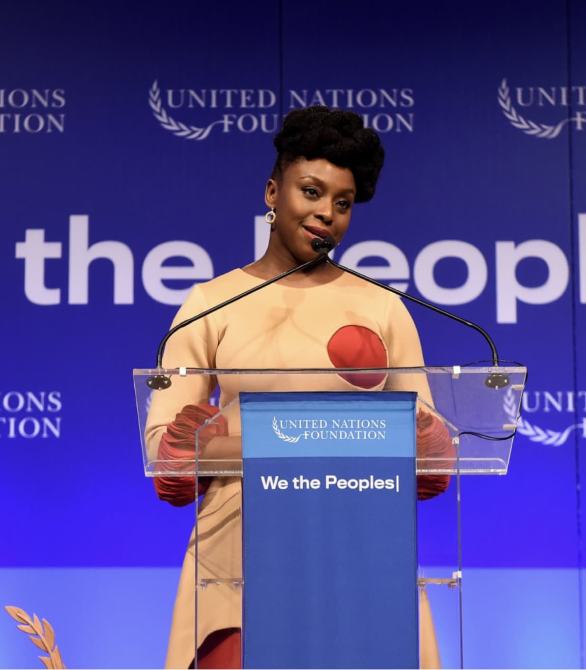 A speaker at a United Nations event, in front of We the Peoples