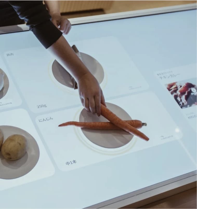 A hand placing food on an interactive Panasonic Well table