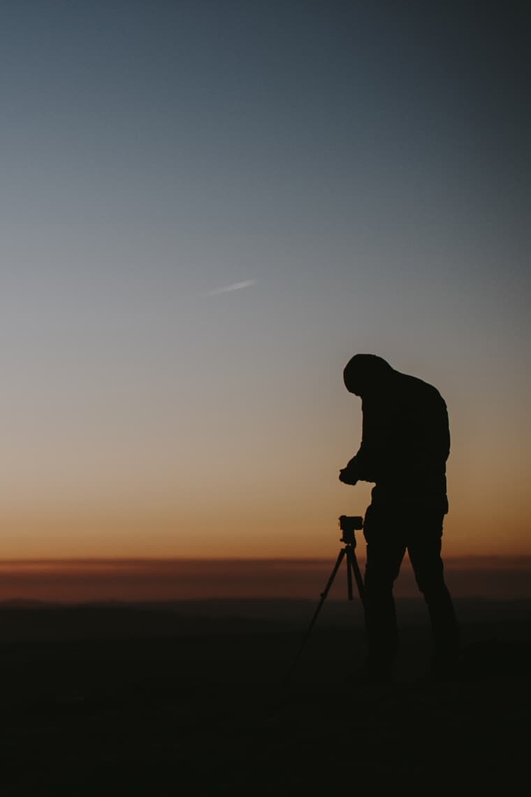 A photographer and tripod silhouetted against the dusk sky