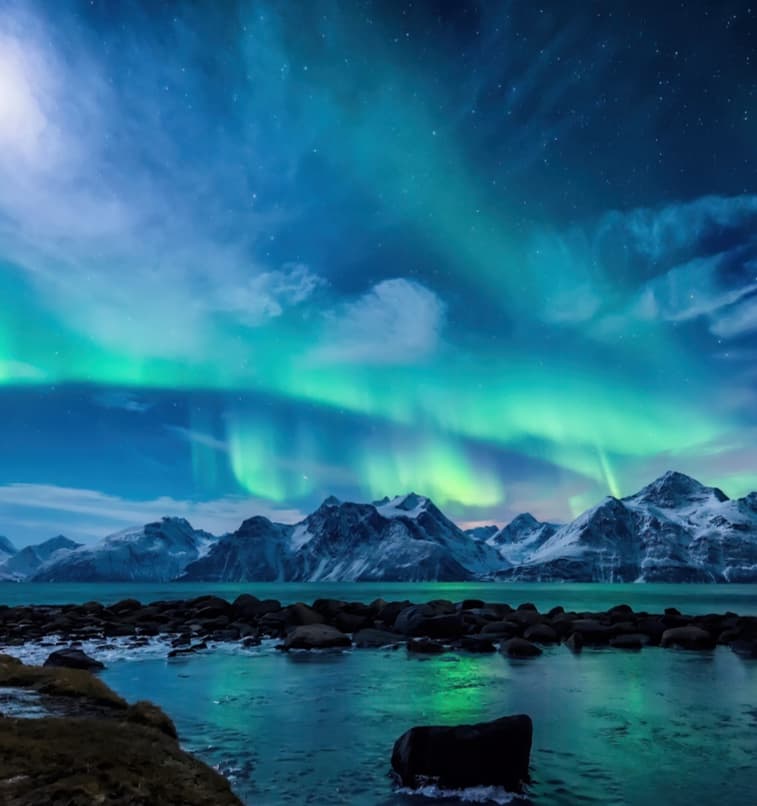 The northern lights over snowy mountains and the sea