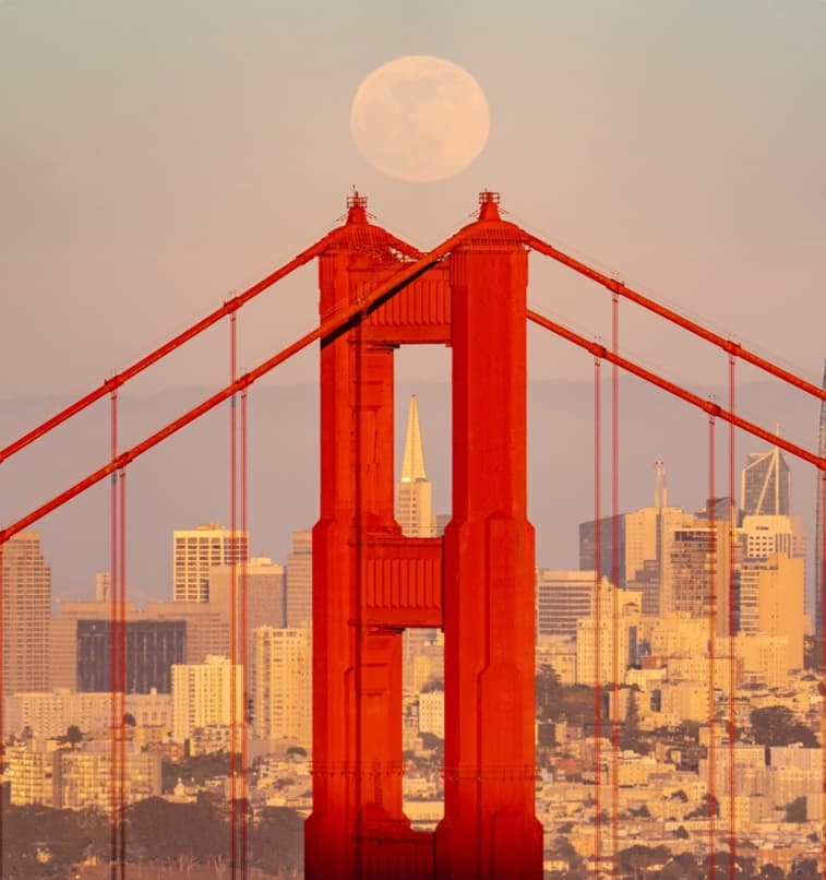 A full moon rising behind the Golden Gate Bridge