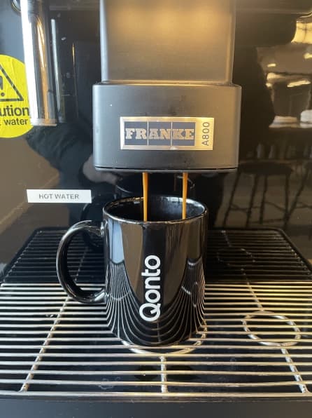 A Qonto mug under the office coffee machine