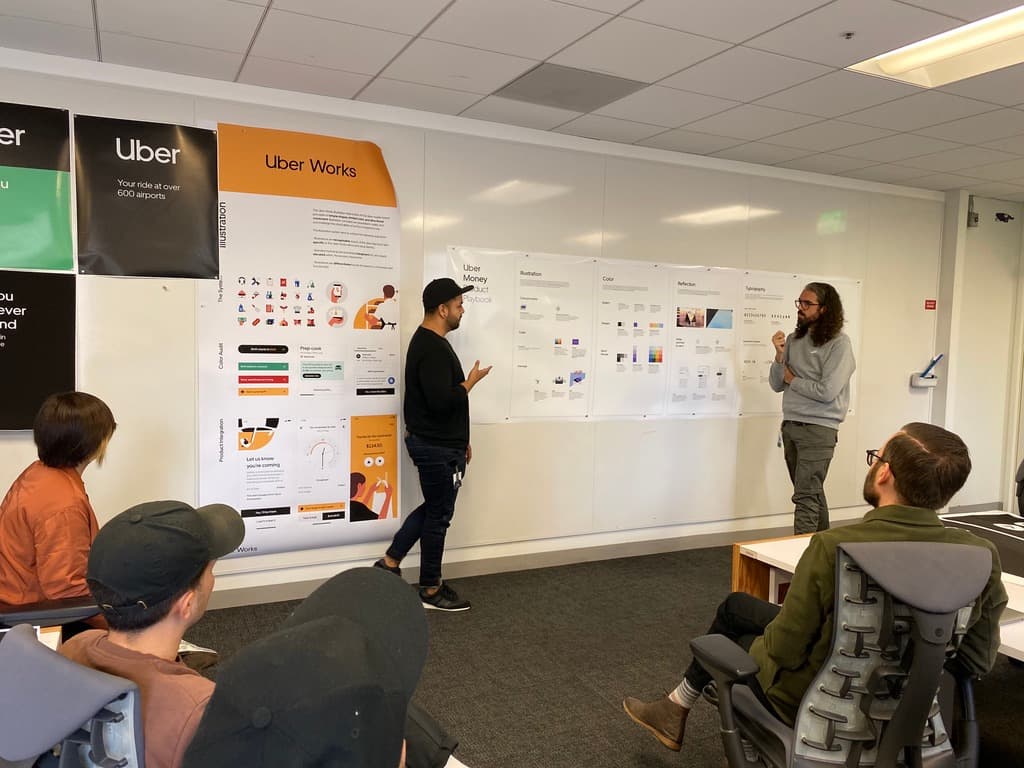 A design review in front of an Uber Works wall